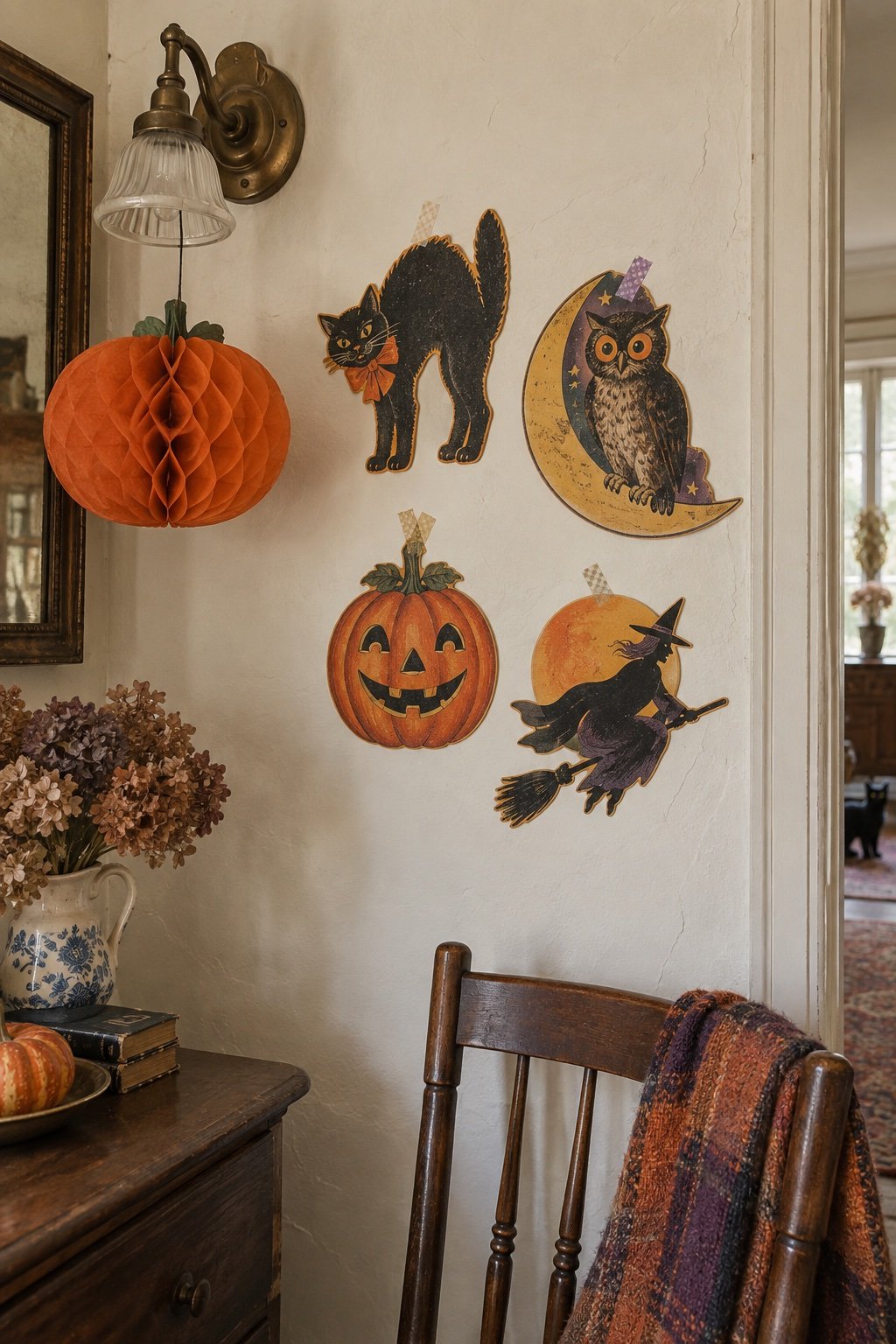A cluster of vintage embossed Halloween die-cuts on a cream wall with a honeycomb tissue pumpkin hanging nearby